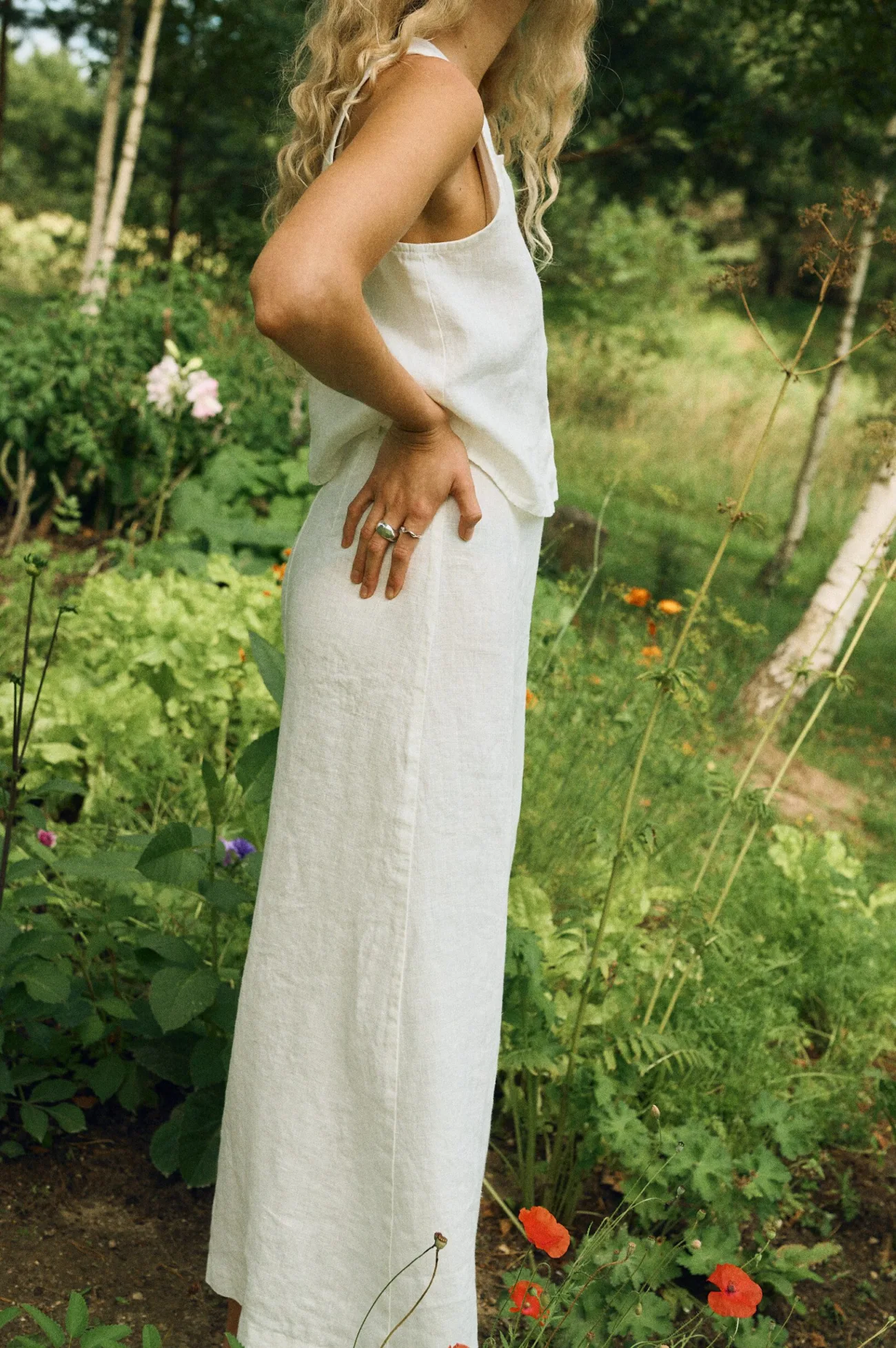 Side view of a summer outfit featuring a sleeveless milky white linen top and a matching high-waisted midi skirt
