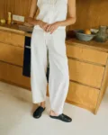 Woman wearing a milky white linen sleeveless button-up top and wide-leg trousers