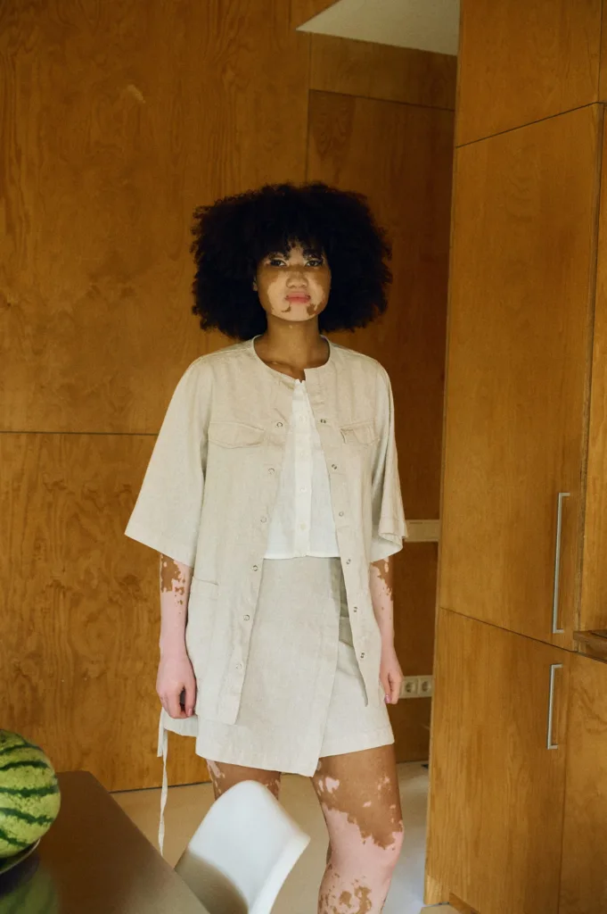 Front view of a natural cotton blend overshirt with wide half sleeves and snap closure, layered over a milky white linen top and paired with a matching natural cotton blend skirt featuring a clean, structured silhouette