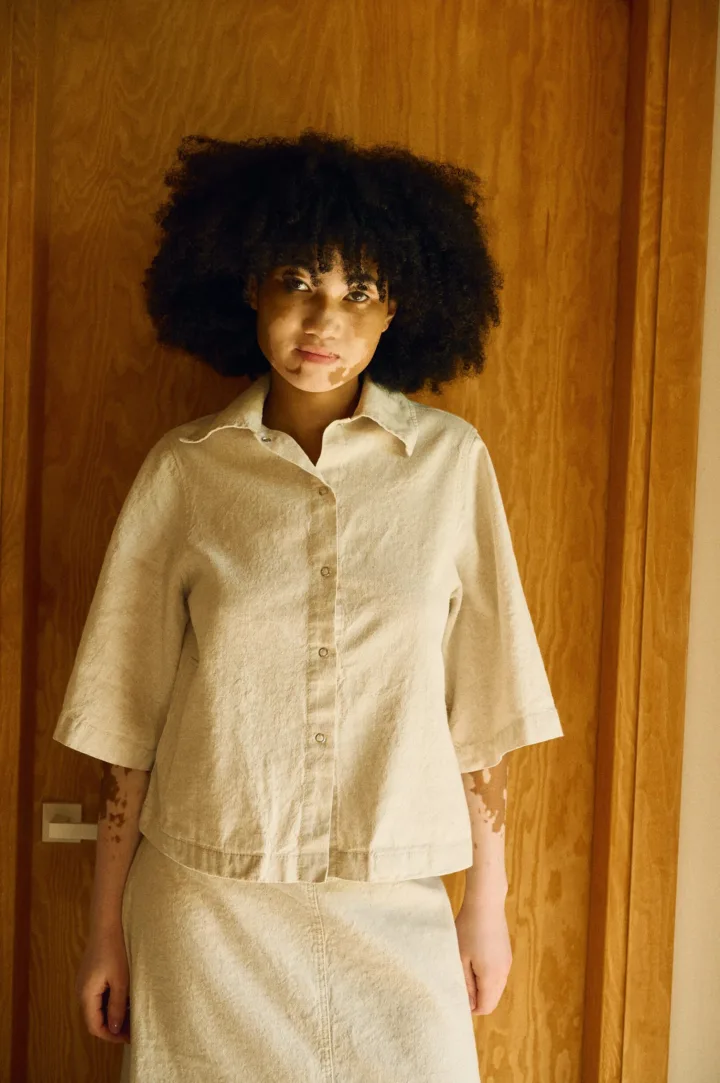 Front view of a natural-toned linen-cotton set featuring a boxy button-up shirt with wide sleeves, paired with a high-waisted midi skirt with a front slit