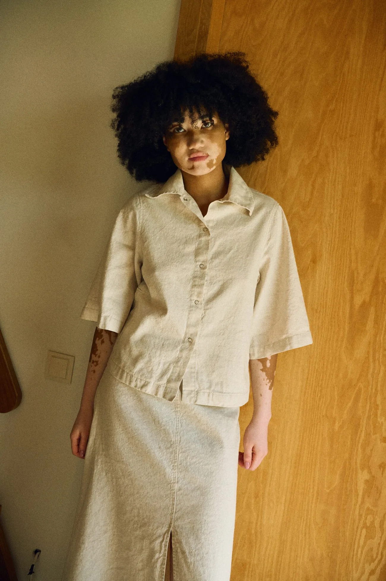 Front view of a natural linen-cotton co-ord set featuring a structured short-sleeve button-up shirt with a pointed collar and a high-waisted A-line midi skirt with a front slit