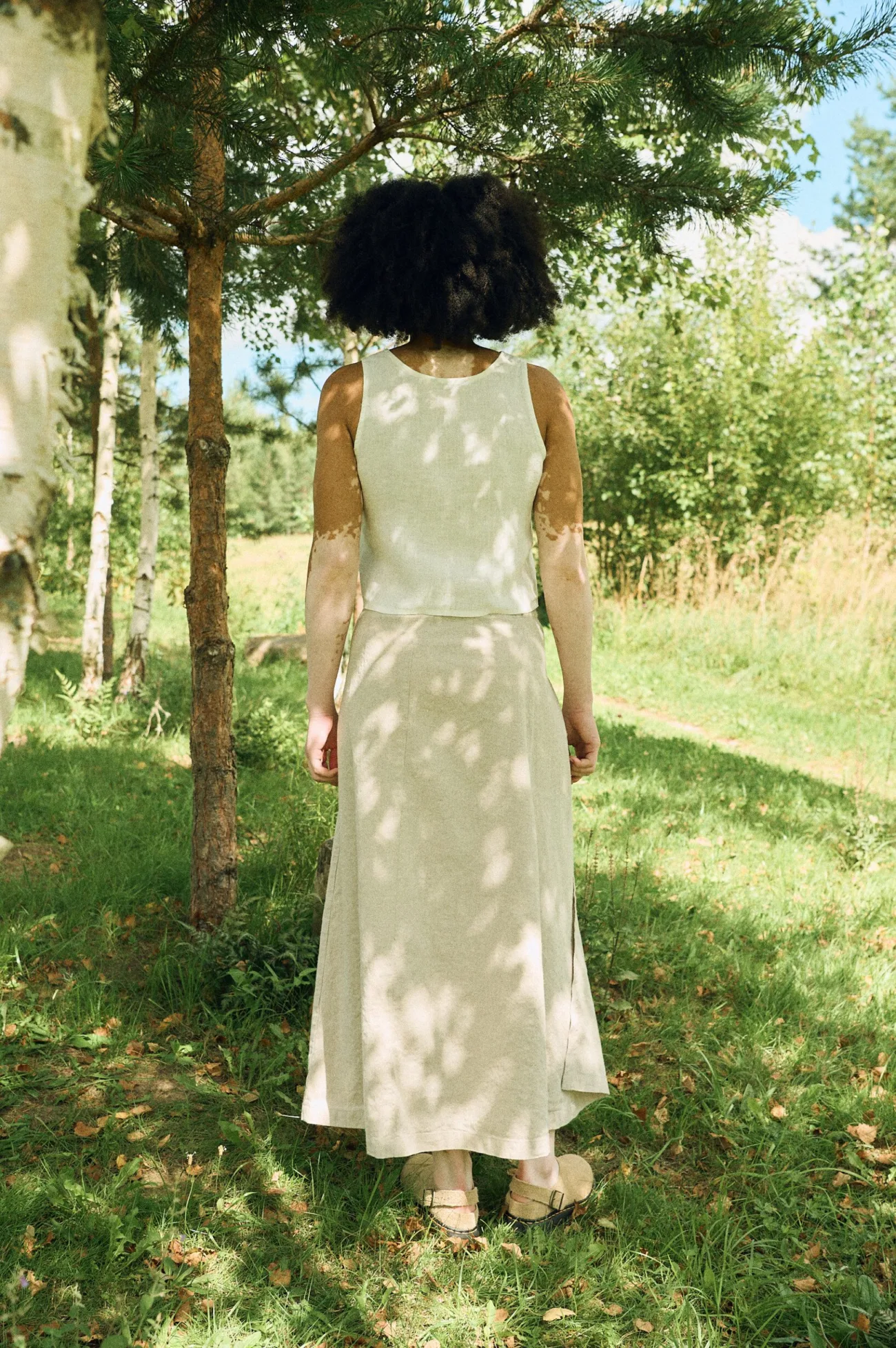 Back view of a woman wearing a natural cotton-linen blend wrap skirt with an A-line silhouette and a sleeveless white linen top