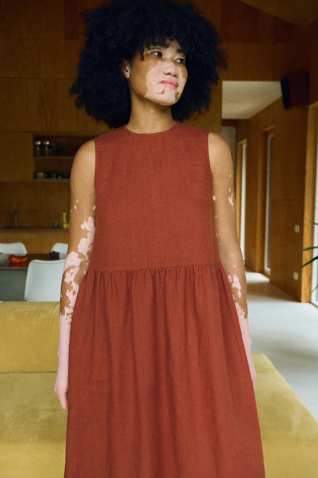 Front view of a woman in a sleeveless terracotta linen dress showcasing its clean, structured bodice and softly gathered skirt for a relaxed, airy silhouette