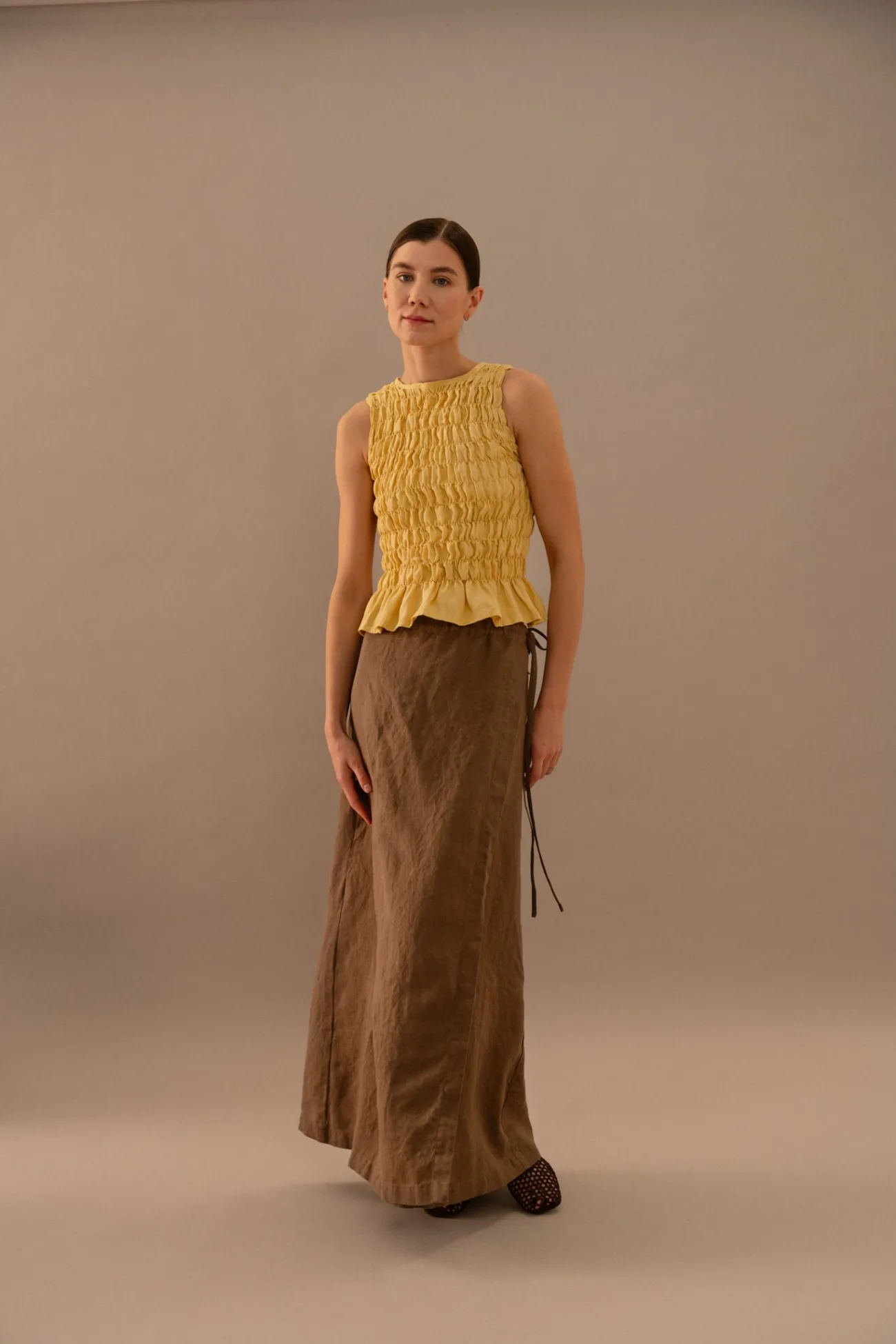 Yellow smocked linen peplum top with textured shirred bodice, paired with brown linen wrap skirt