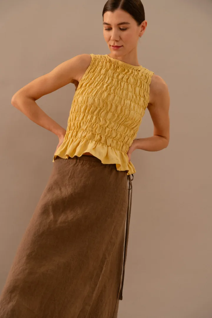 Close-up of yellow linen smocked top showing gathered texture and fitted silhouette