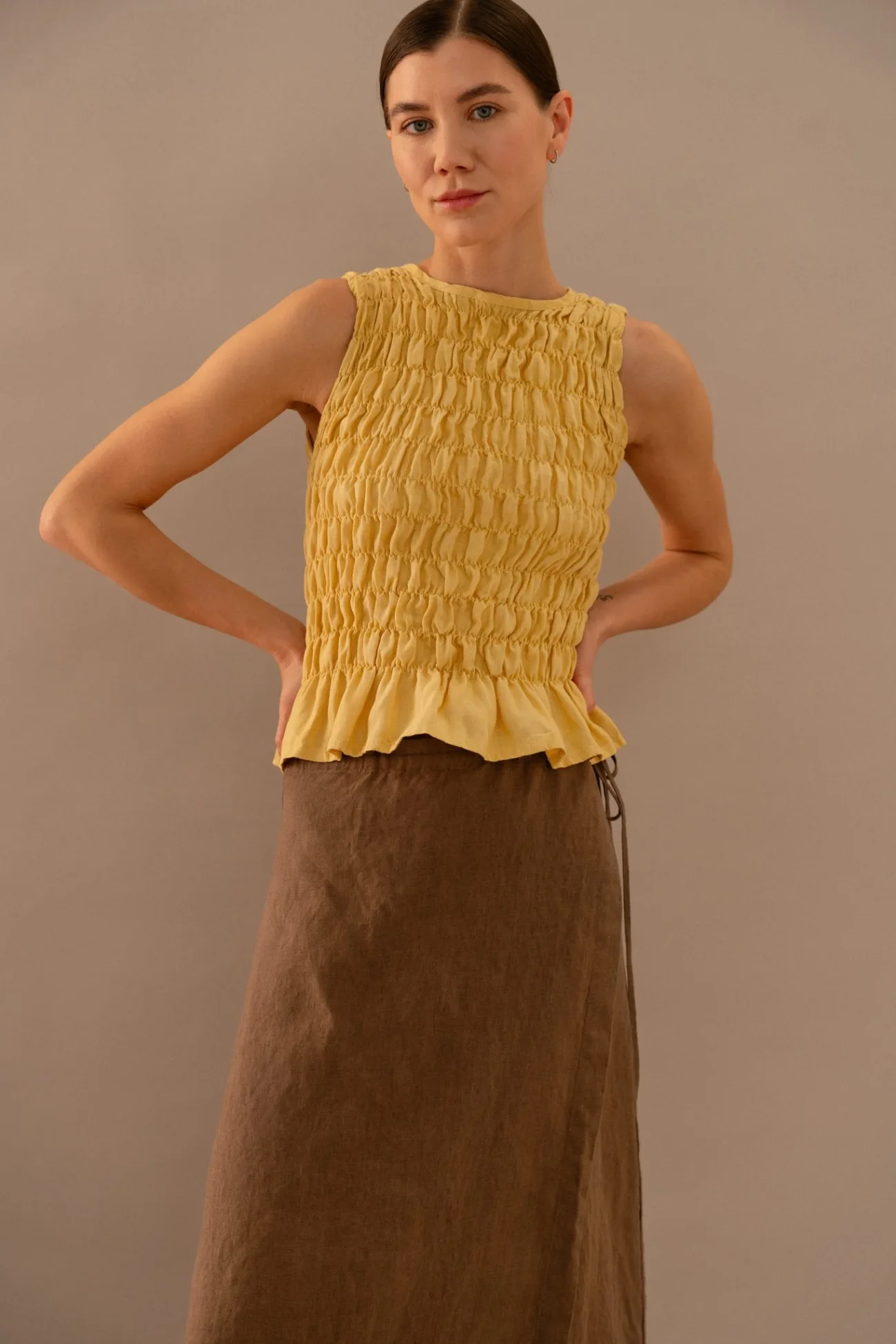 Butter yellow sleeveless smocked top with soft ruffled hem styled with brown linen maxi skirt