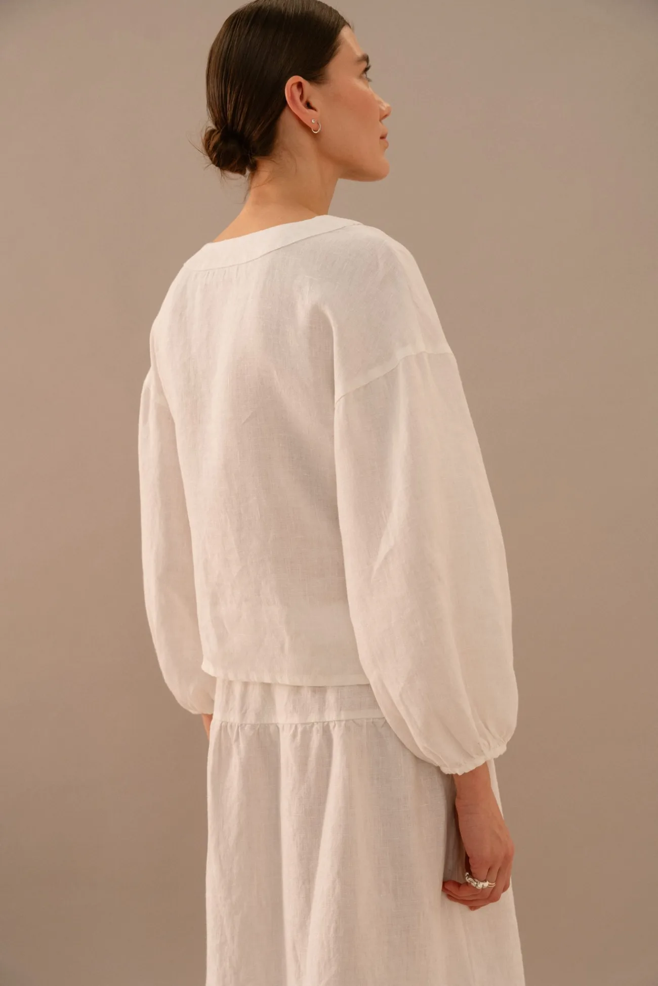 Back view of milky white linen wrap top with long sleeves and matching tiered maxi skirt