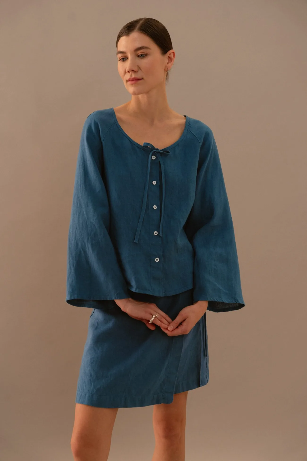 Stellar blue linen blouse with front buttons and tie neckline paired with matching wrap mini skirt