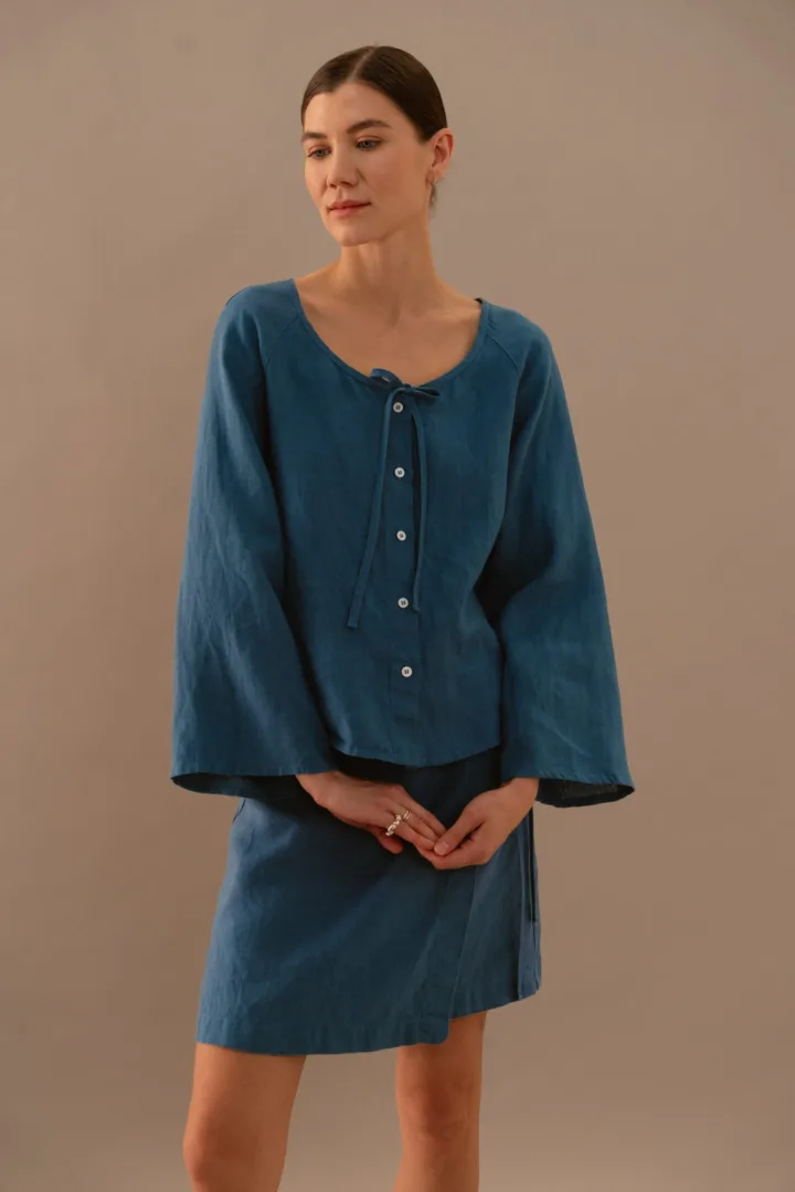 Stellar blue linen blouse with front buttons and tie neckline paired with matching wrap mini skirt
