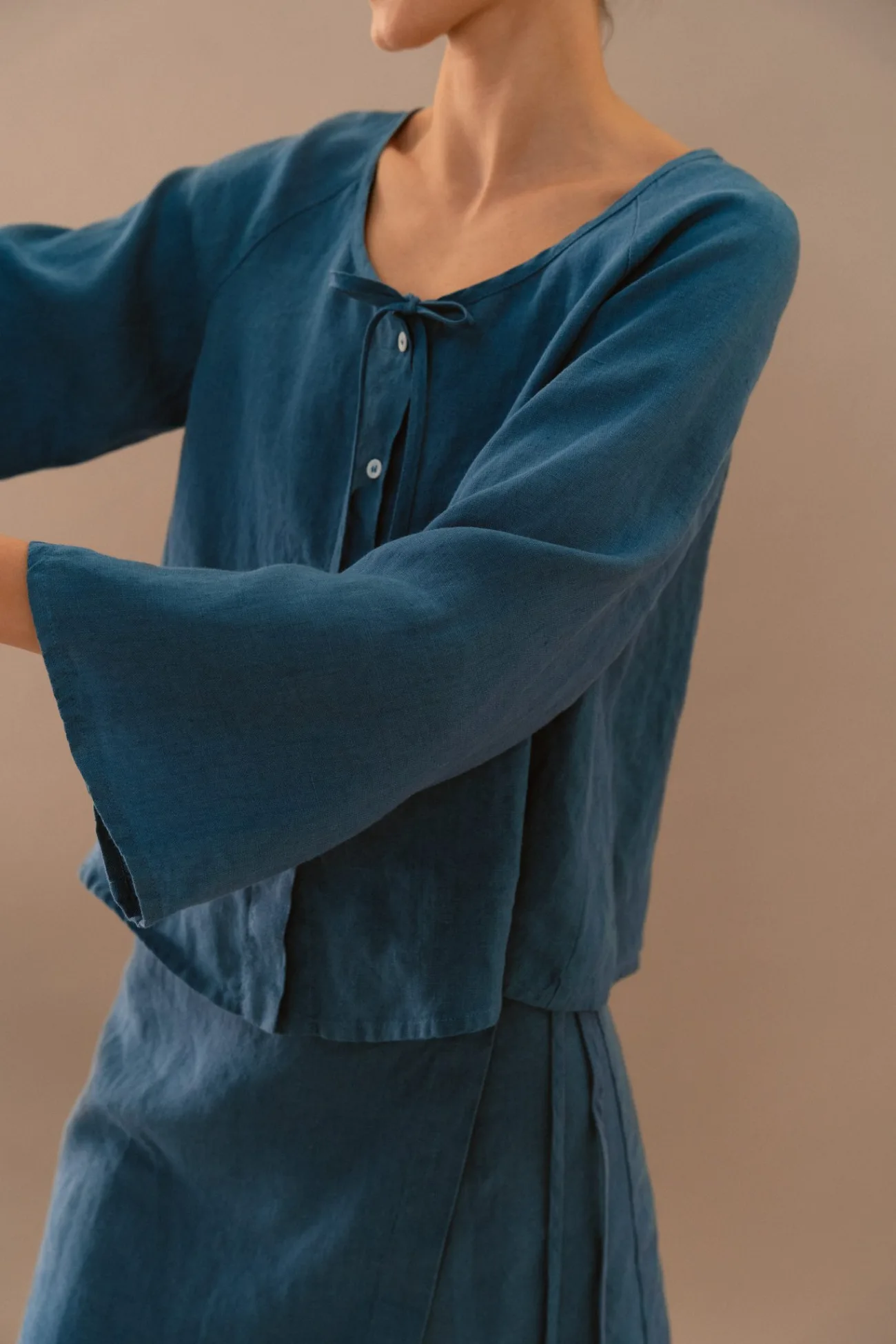 Close-up of stellar blue linen blouse with tie neckline and wide sleeves