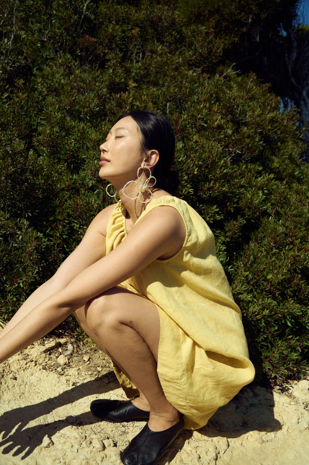 close-up of woman sitting down in butter yellow mini linen dress