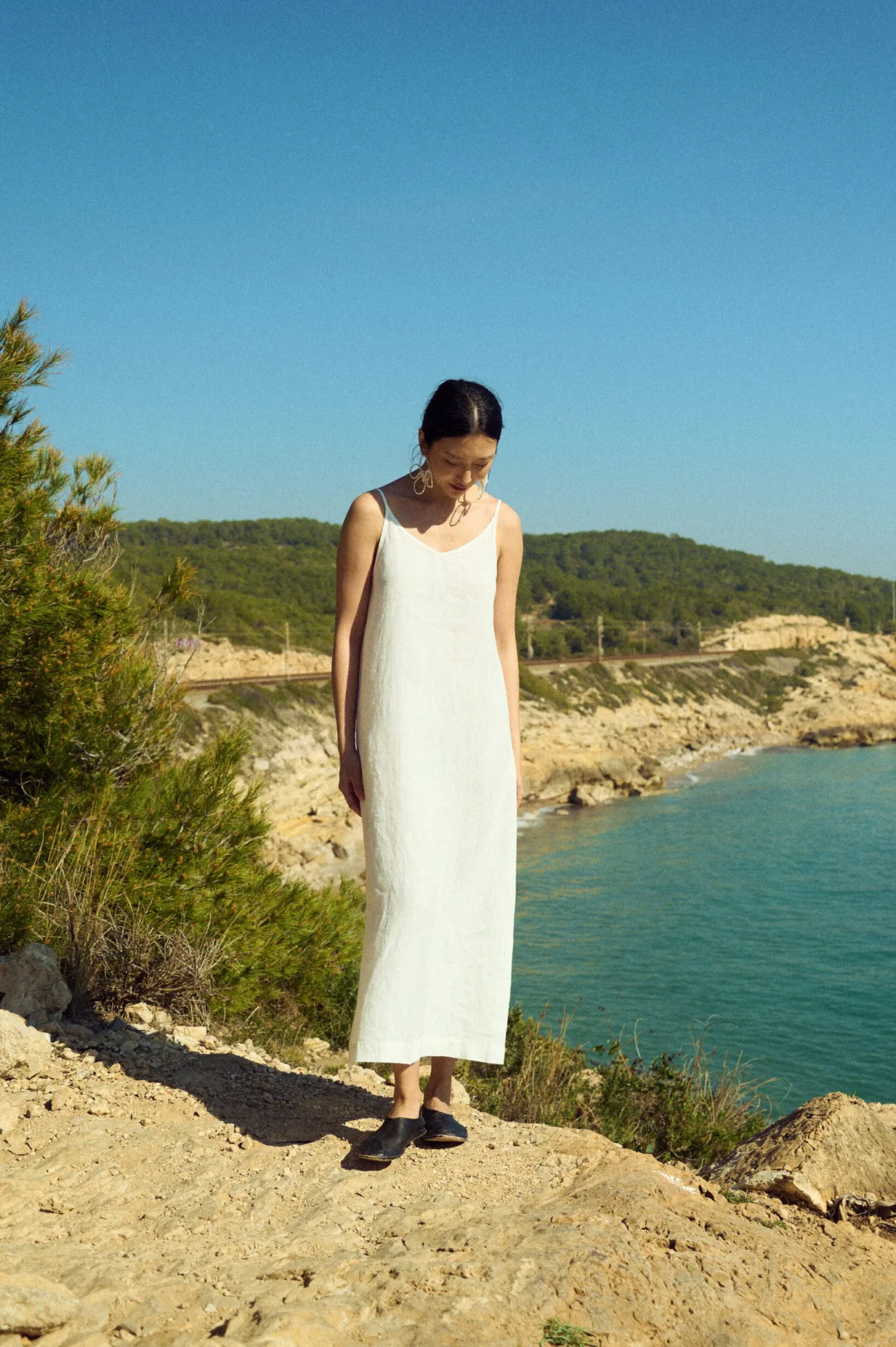 Minimalist white linen slip dress with thin straps styled for summer by the coast