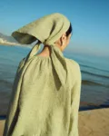 Back view of a moss green mini gingham linen triangle scarf tied at the nape, worn with a matching airy gingham blouse