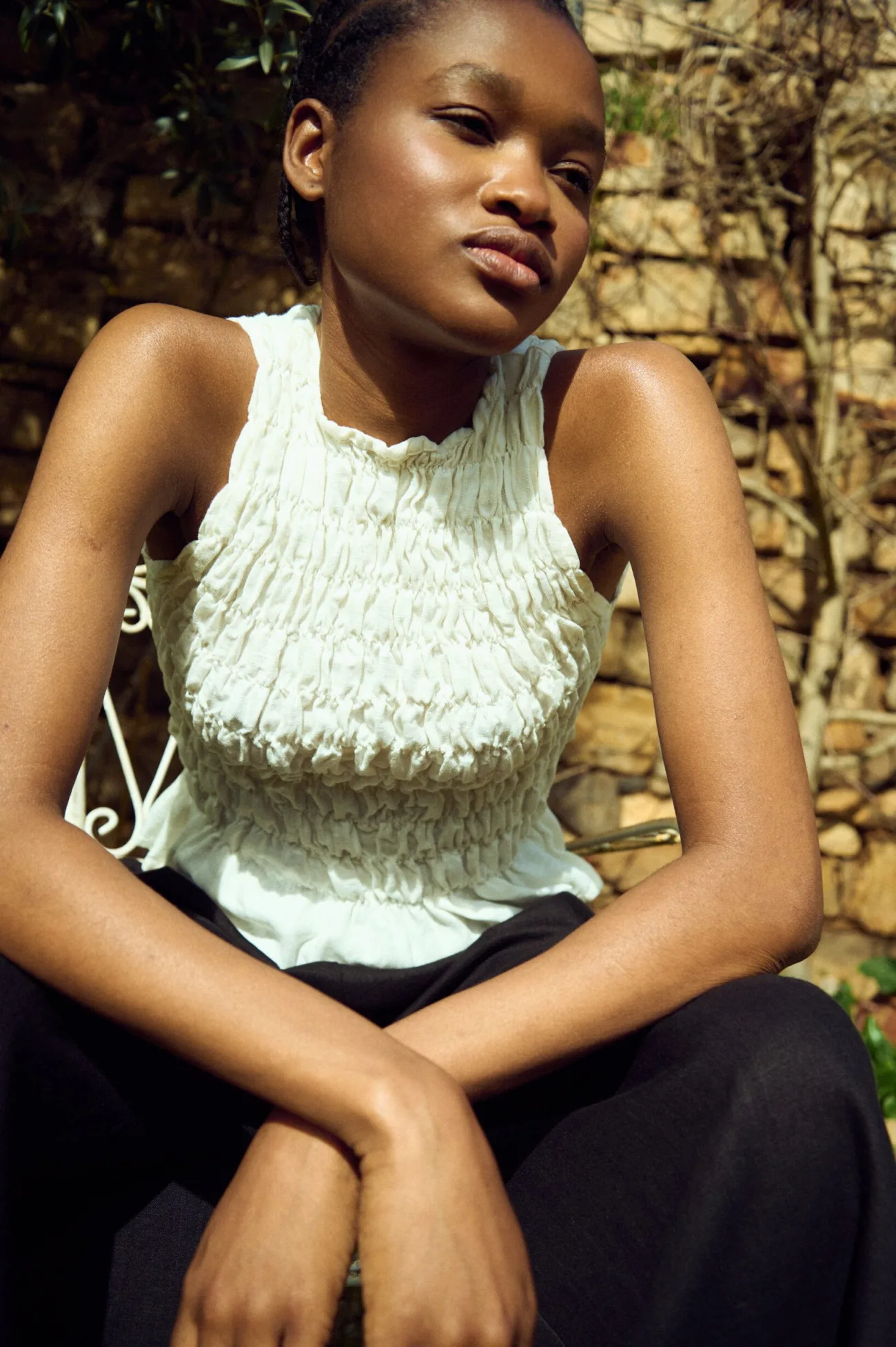 Sleeveless white linen top with all-over smocking and soft peplum hem