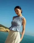 Blue gingham linen smocked top with gathered texture and soft peplum hem, paired with a natural linen cotton blend wrap skirt