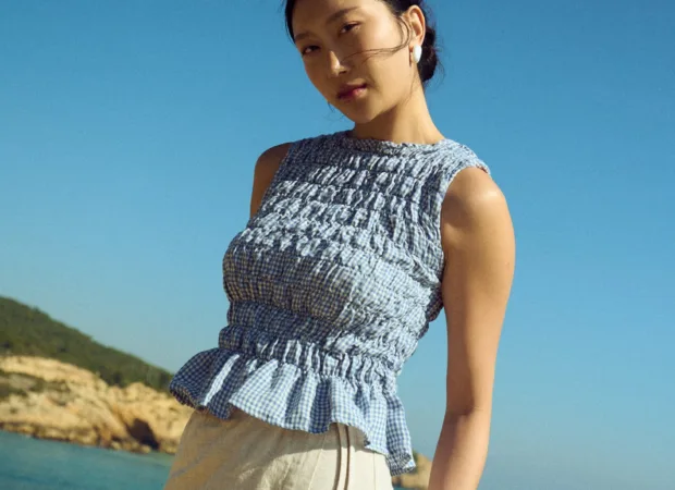 Blue gingham linen smocked top with gathered texture and soft peplum hem, paired with a natural linen cotton blend wrap skirt