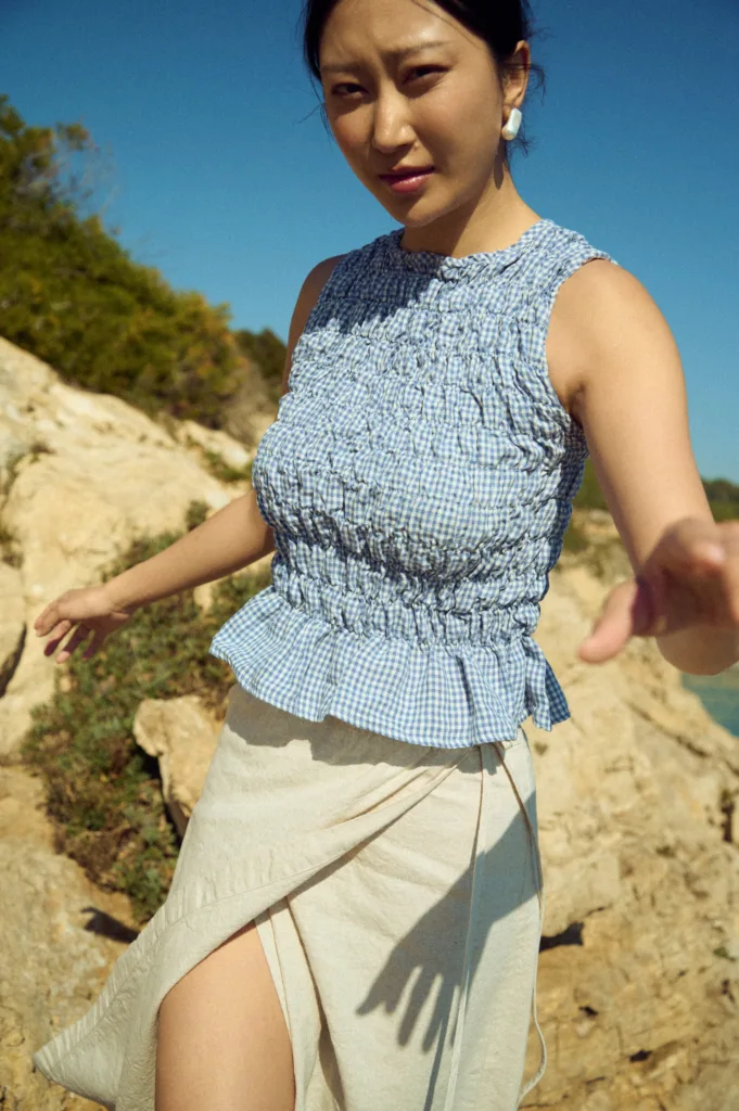 Blue gingham linen smocked top with sculpted fit and delicate volume at the hem, worn with a natural linen cotton blend skirt