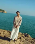 Brown gingham linen wrap top with soft V neckline and adjustable side tie, paired with a white linen skirt