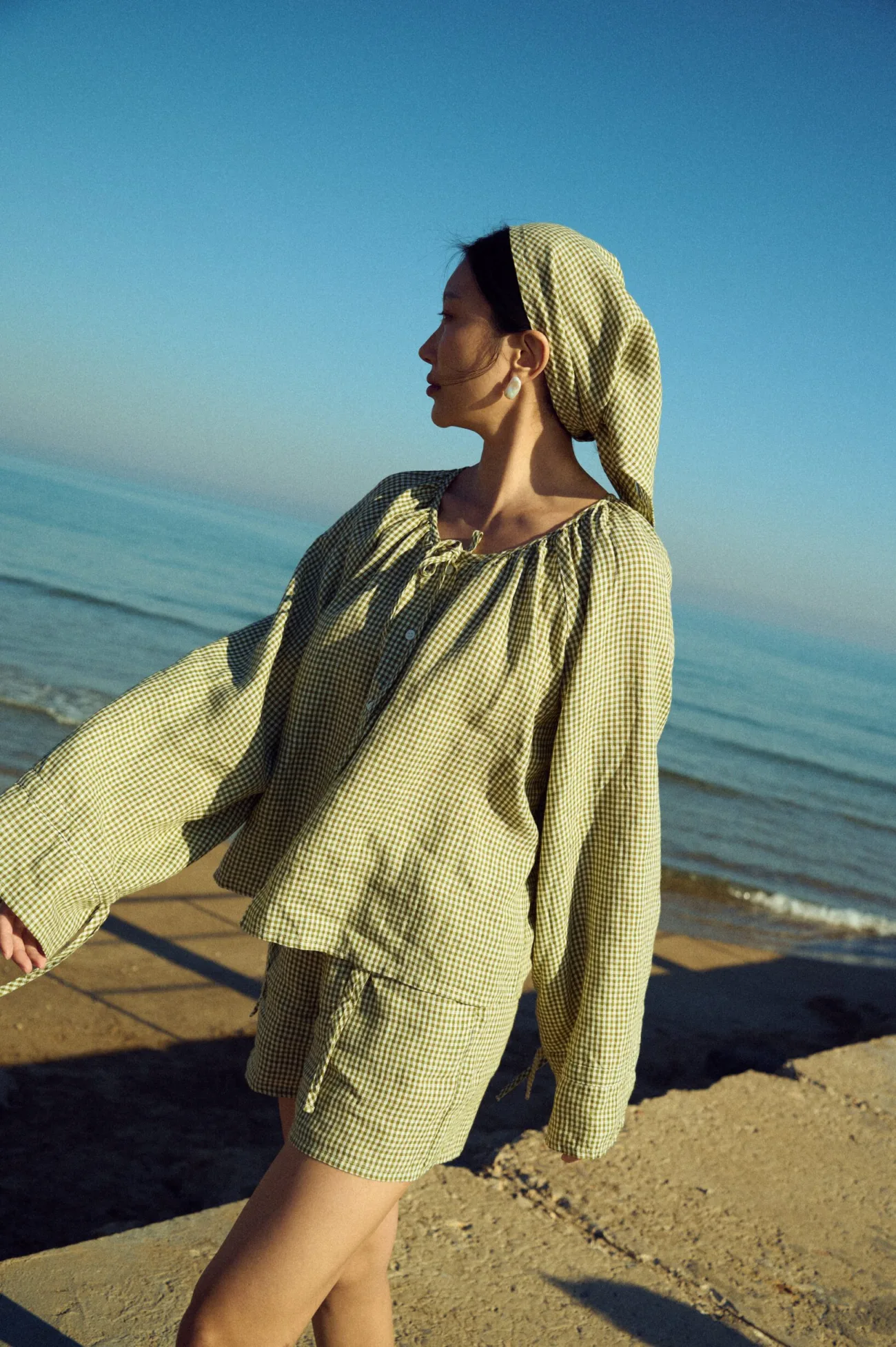 Moss green mini gingham linen outfit with loose-fitting top and wide sleeves, paired with matching shorts and headscarf