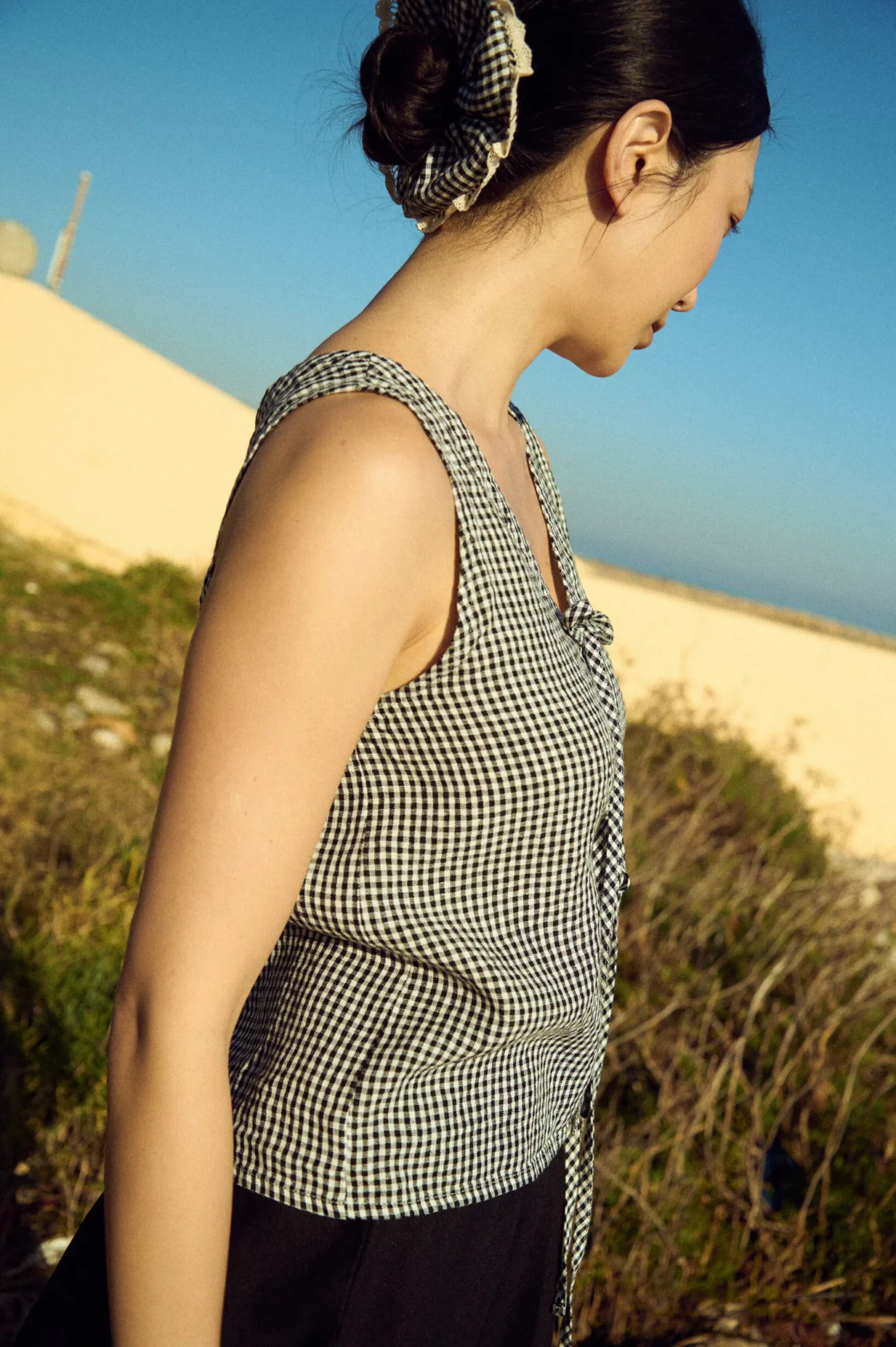 Side view of black gingham linen sleeveless top with front tie detail