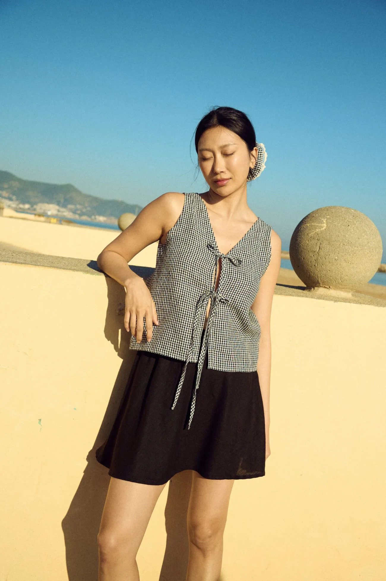 Tie-front black gingham linen top paired with a black linen mini skirt in a relaxed silhouette