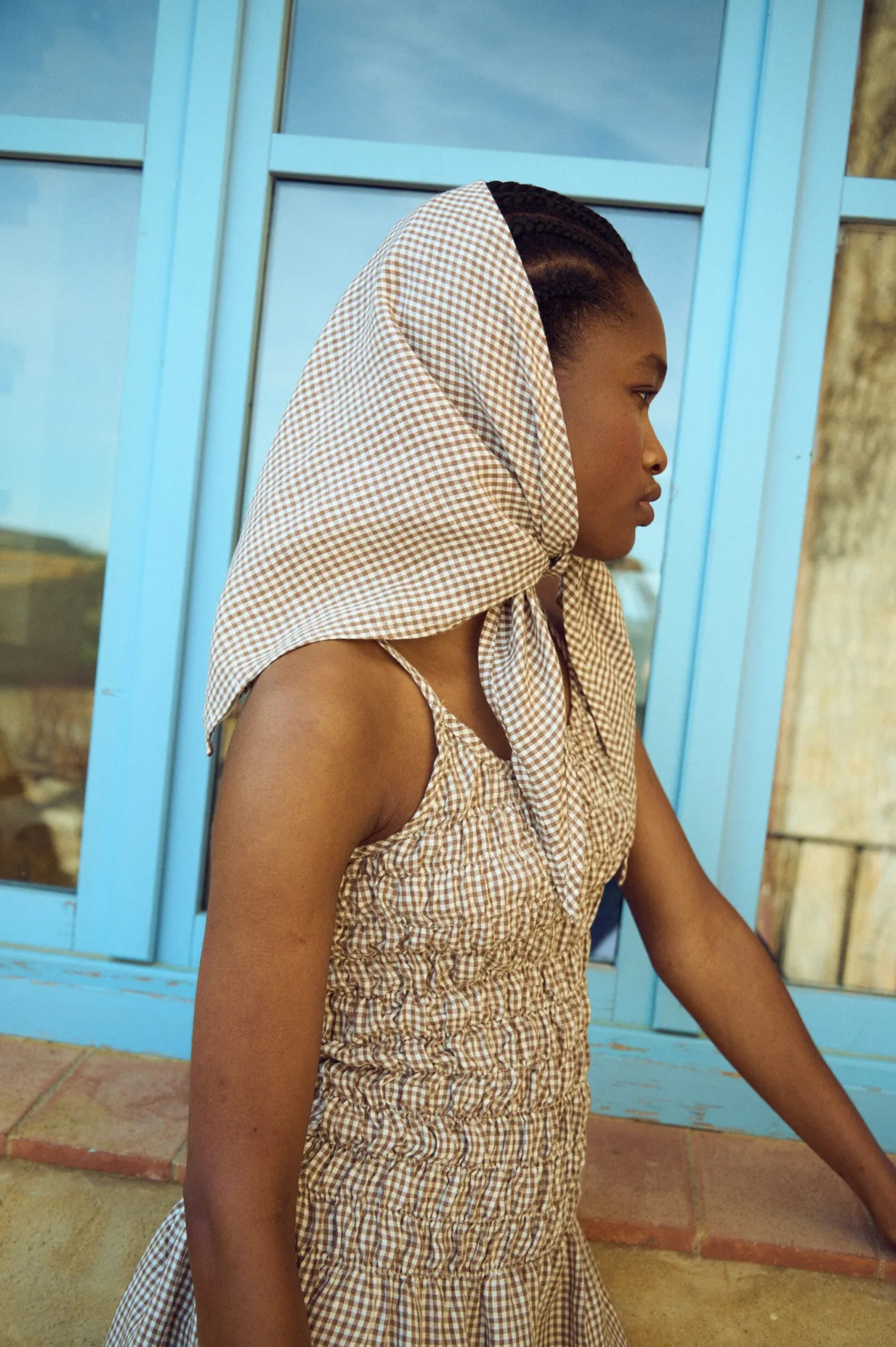 Triangle scarf in brown mini gingham linen styled as a head covering with a gathered gingham dress