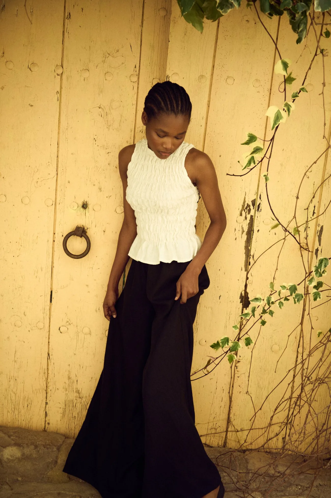model wearing white linen smocked tank top and black linen culottes