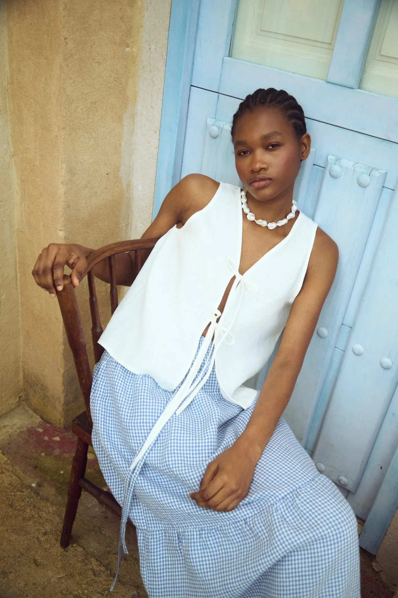 model wearing white linen tie front top and tiered gingham linen skirt