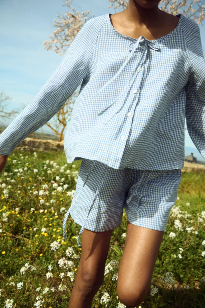 Blue gingham linen top with clean shell button front and relaxed sleeves, paired with coordinating shorts