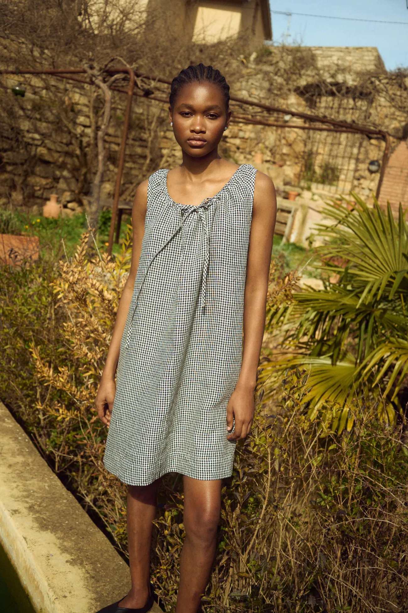 Sleeveless black gingham linen mini dress with soft gathering at the neckline and airy drape
