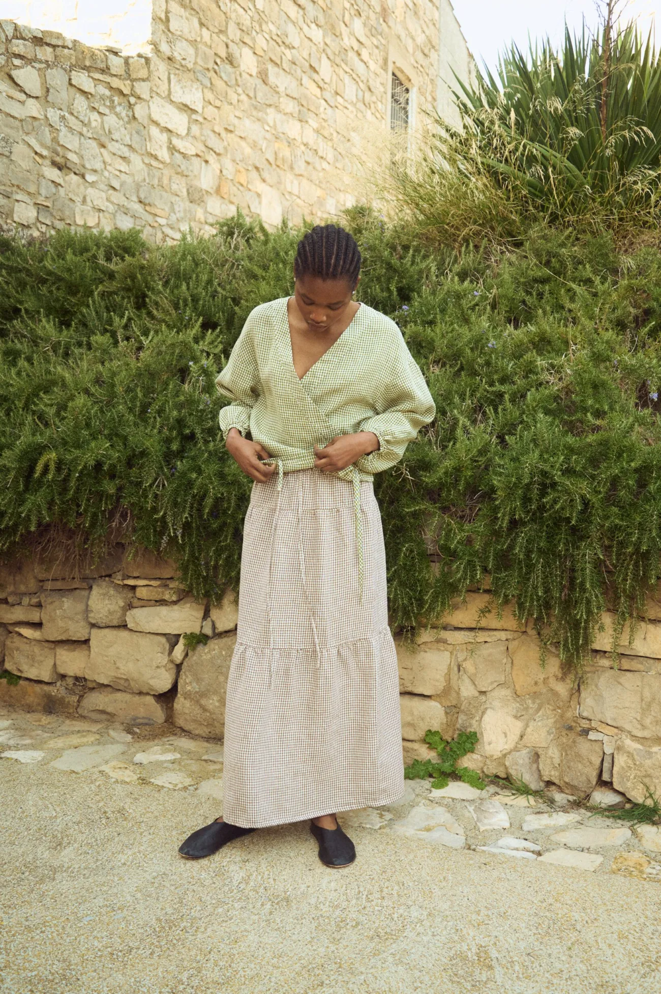 Brown gingham linen long skirt featuring a softly gathered lower panel and fluid drape, styled with a lightweight wrap blouse