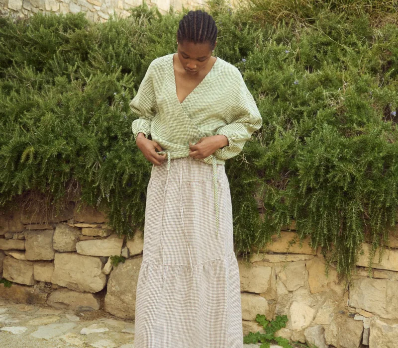 Brown gingham linen long skirt featuring a softly gathered lower panel and fluid drape, styled with a lightweight wrap blouse