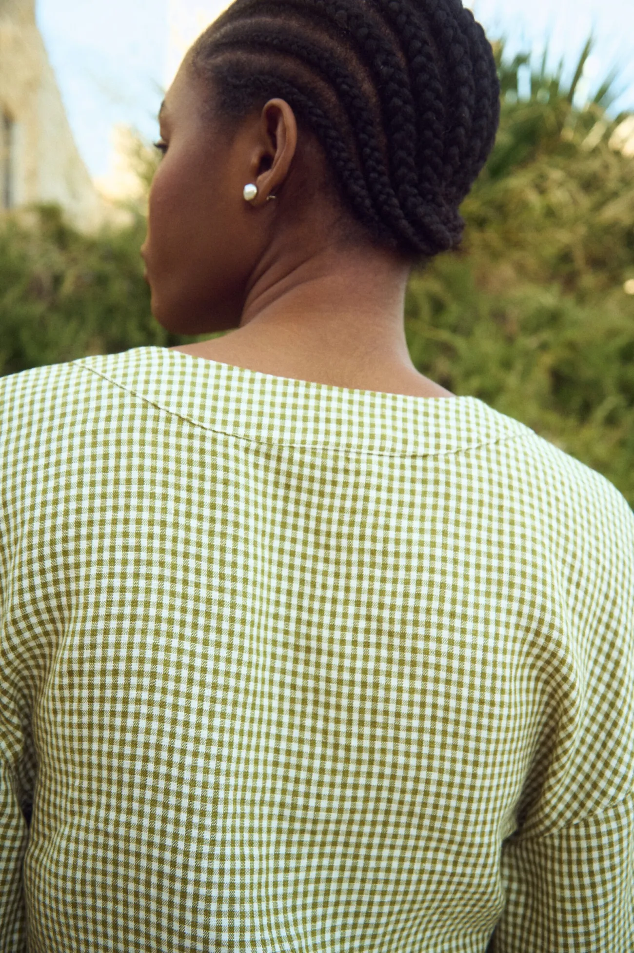 Close-up back view of green gingham linen top with clean neckline and fluid structure