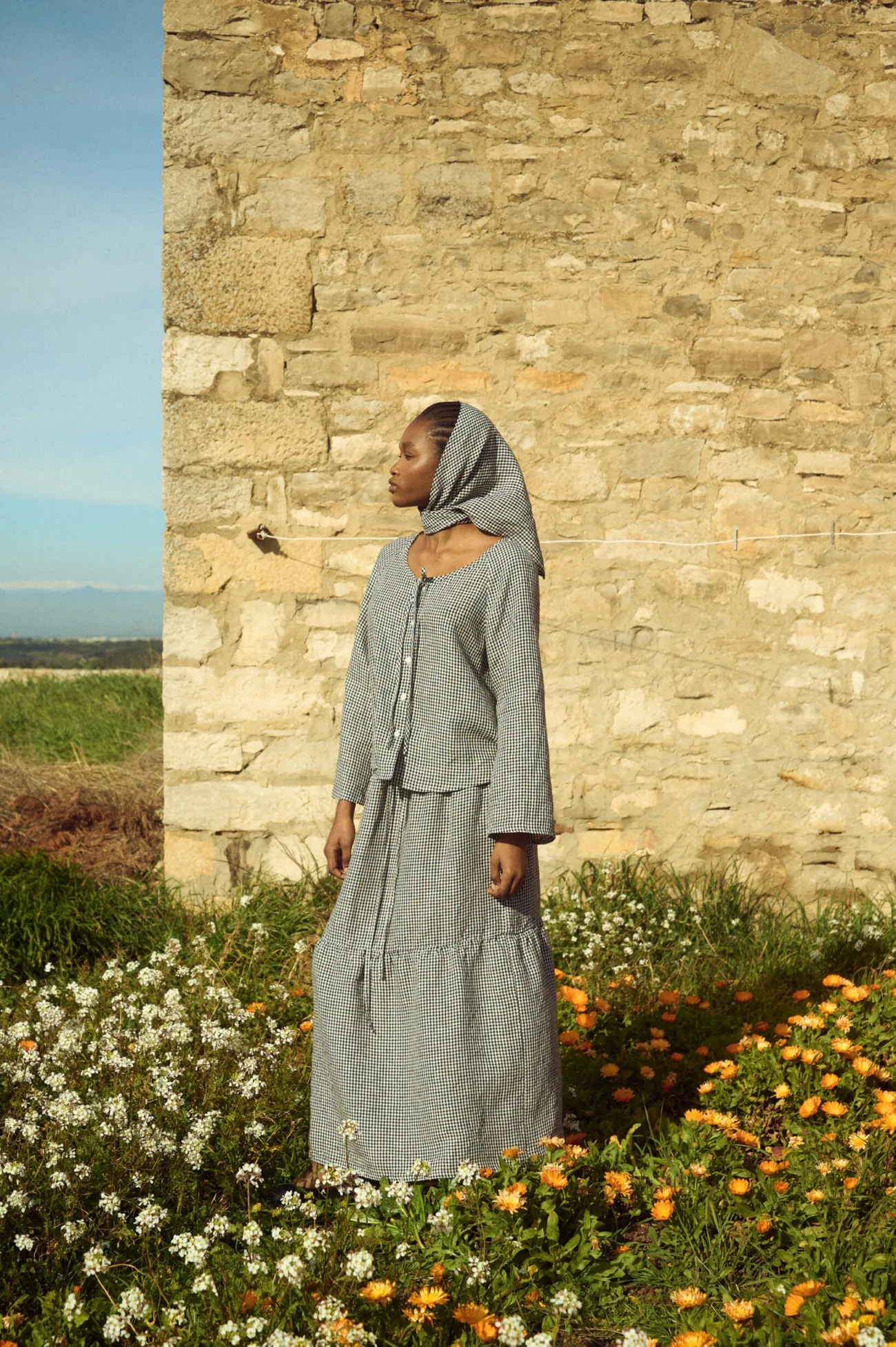 Black gingham linen maxi skirt featuring a softly gathered lower panel and fluid drape, styled with a coordinating linen top and headscarf