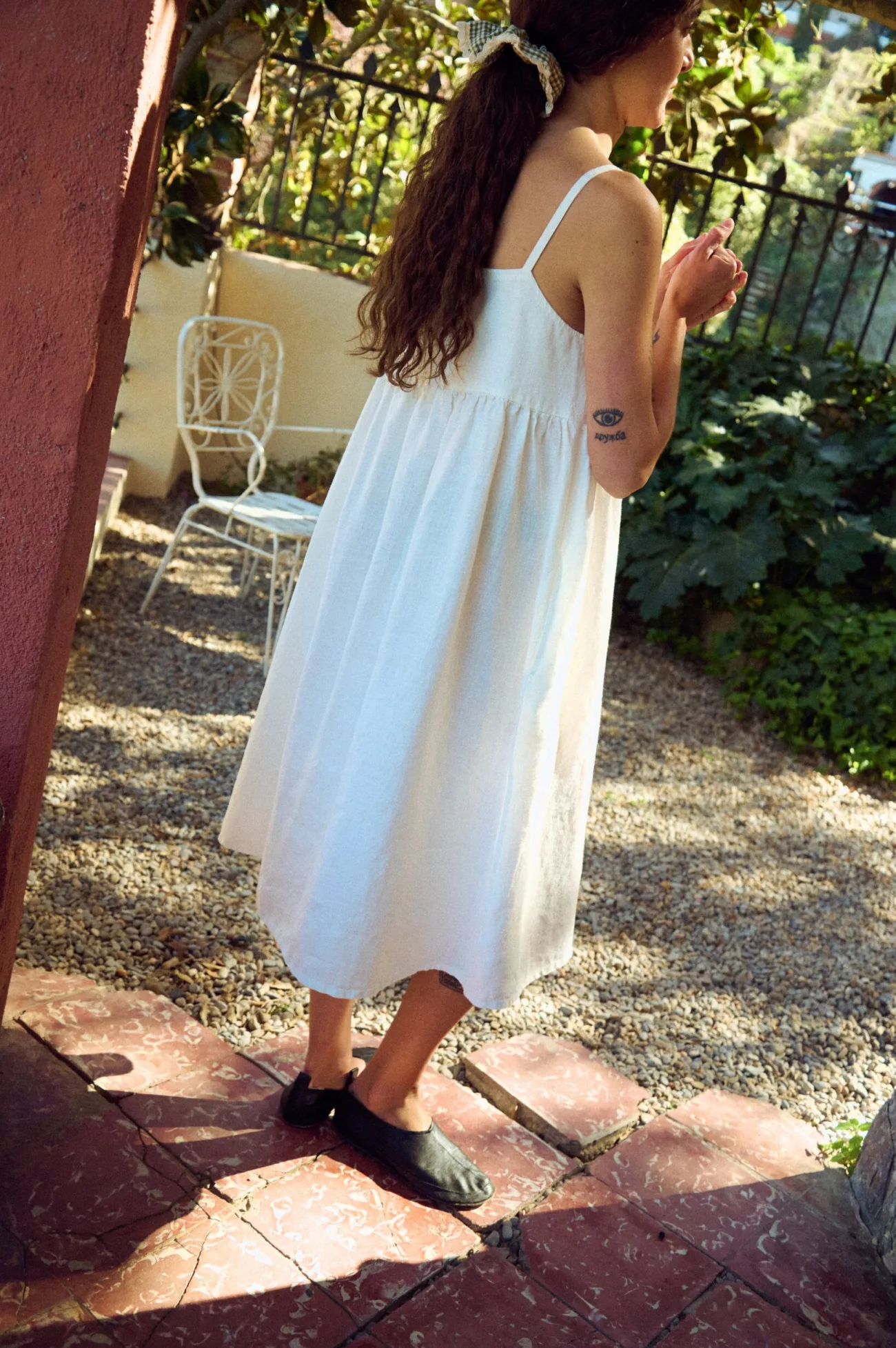 the back view of white linen summer strap dress with gathered flowy skirt