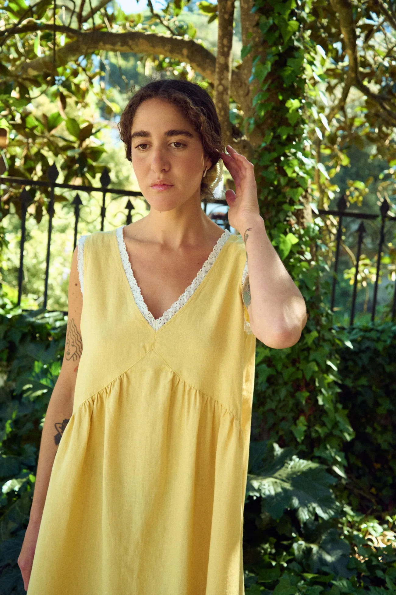 Close front view of butter yellow linen sleeveless midi dress with lace-trim V-neck and armholes, and a softly gathered waist
