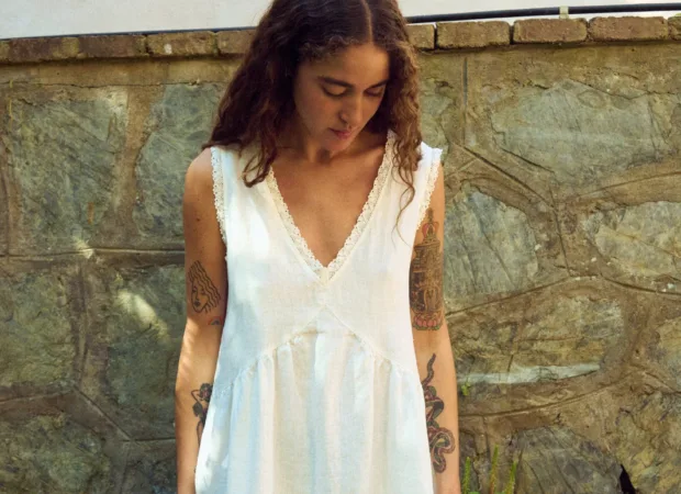 Close front view of milky white linen sleeveless midi dress with V-neck, lace-trim neckline, and softly gathered waist