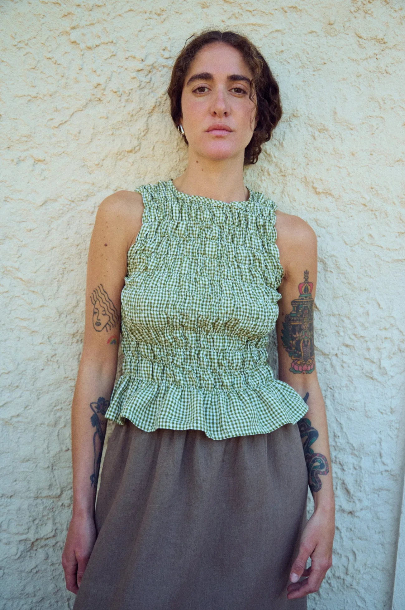 woman wearing moss green gingham smocked top with flared hem