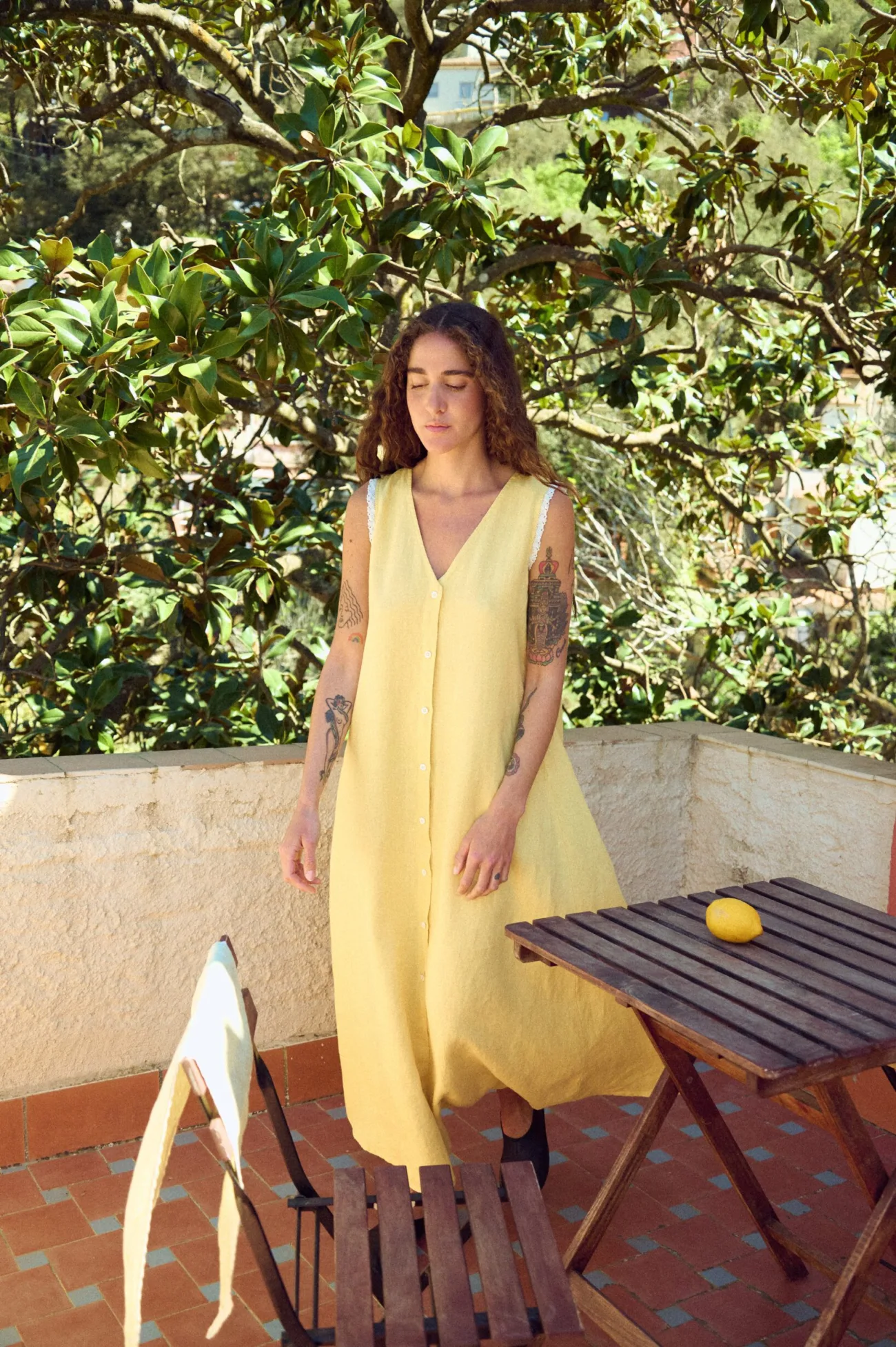 Front view of yellow linen sleeveless maxi dress with button placket, V-neckline, lace-trim edges, and loose flowing silhouette