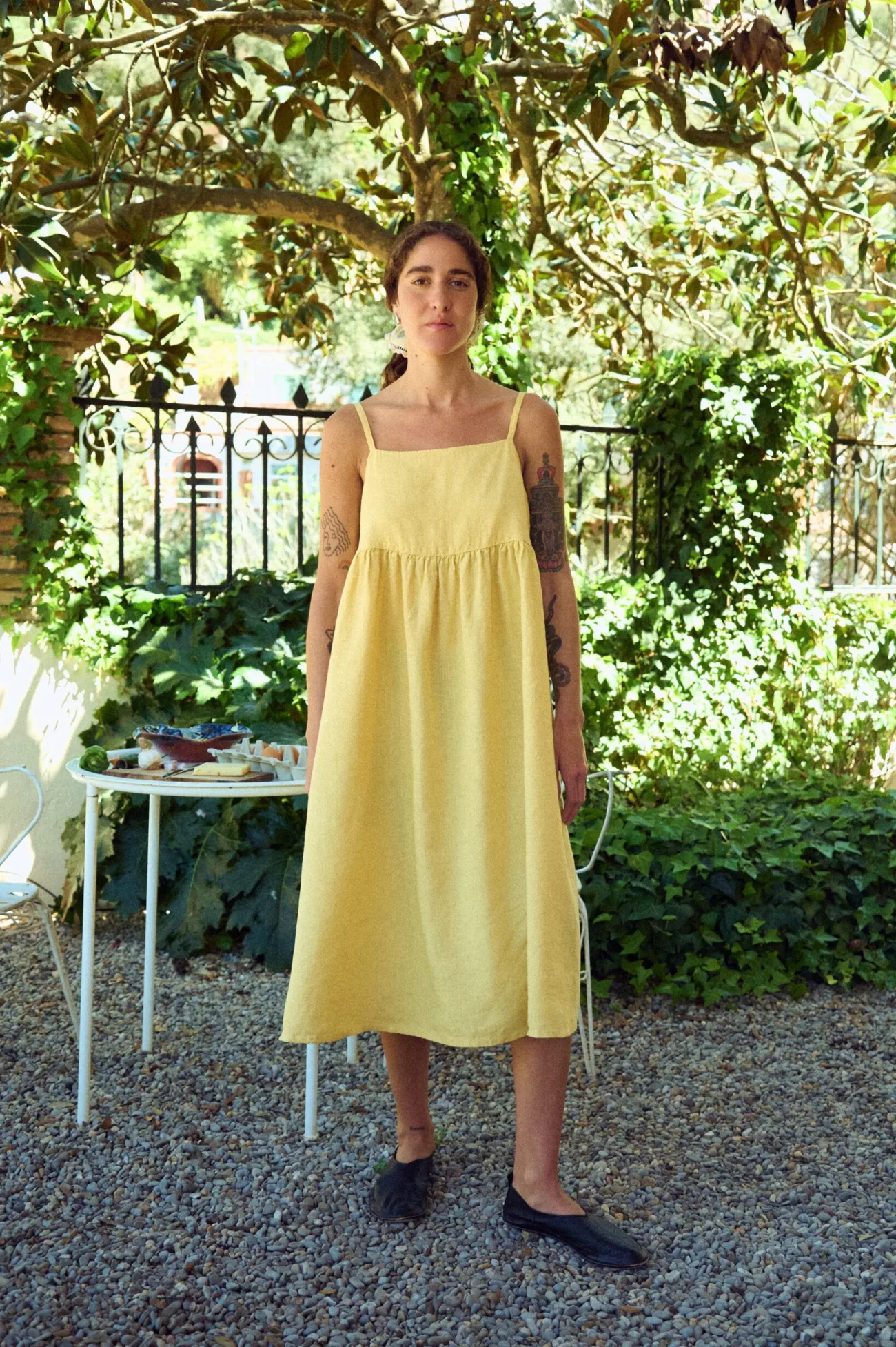 woman posing with butter yellow strap dress in midi length and flowy skirt