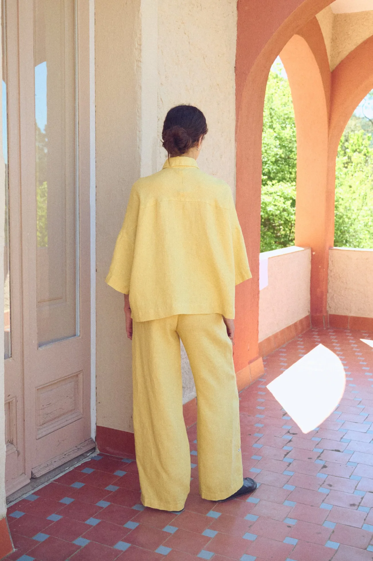 the back view of oversized butter linen shirt with loose fit, paired with wide linen pants