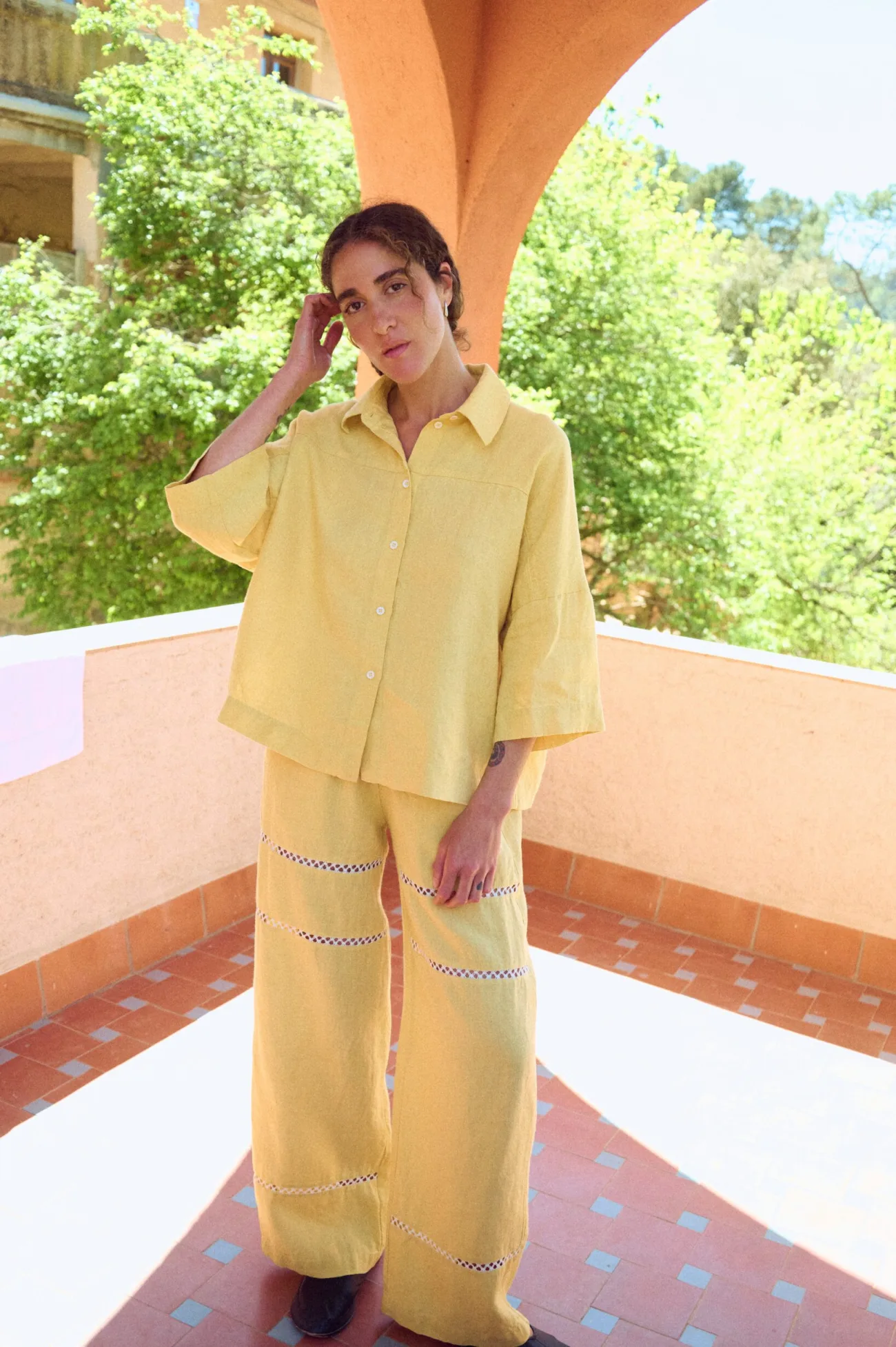 woman wearing butter yellow linen set with oversized button down shirt and summer pants with lace details