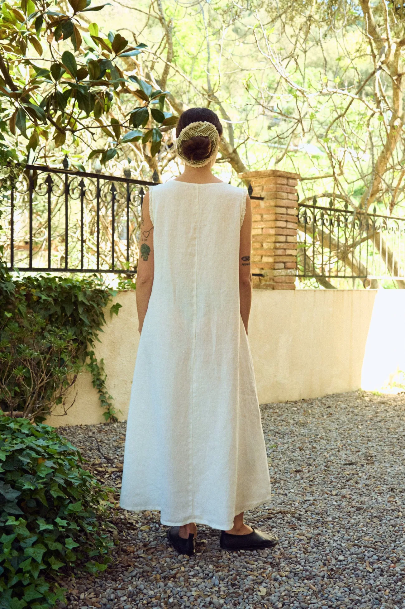 Back view of the white linen dress showing its clean, sleeveless cut and softly flared silhouette