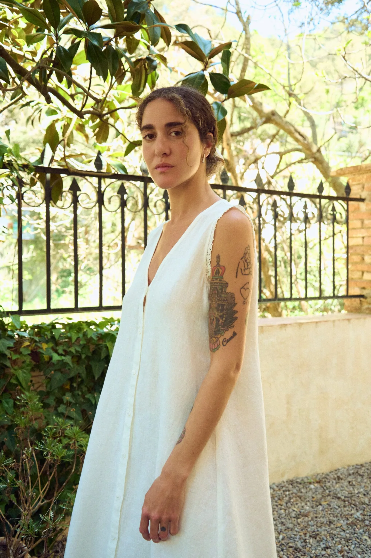 Close side view of milky white linen sleeveless maxi dress with V-neck, button front, and delicate lace-trimmed armholes