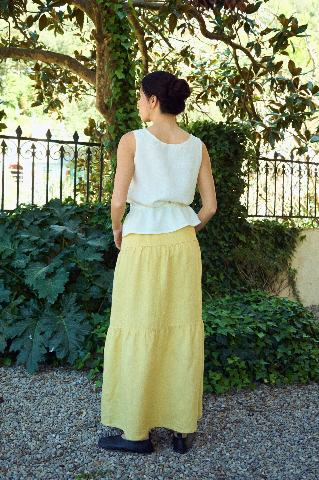back view of tiered linen skirt in butter, and sleeveless blouse in white linen fabric