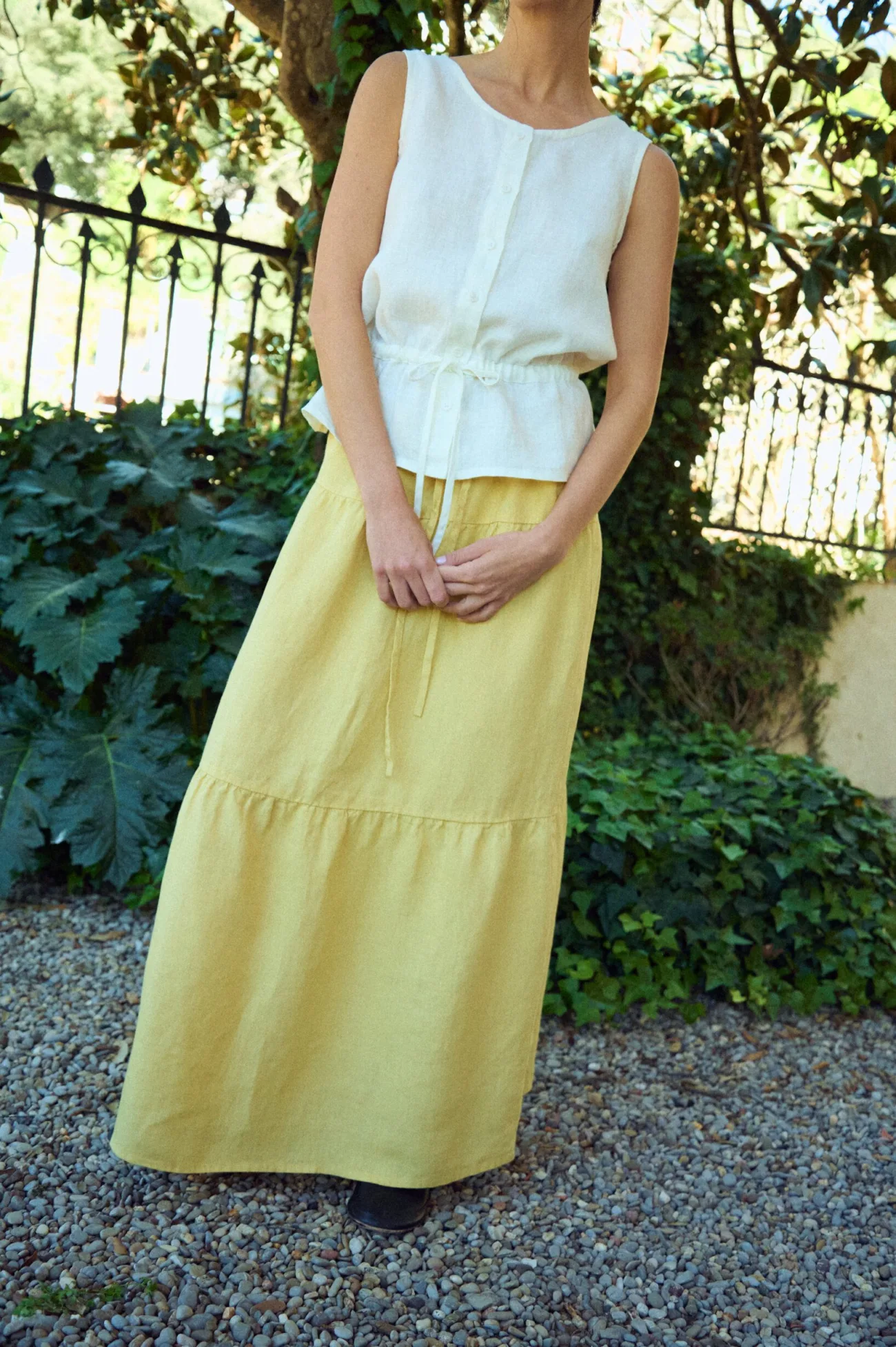 front view of tiered linen skirt in butter styled with white sleeveless linen blouse with gathered waist