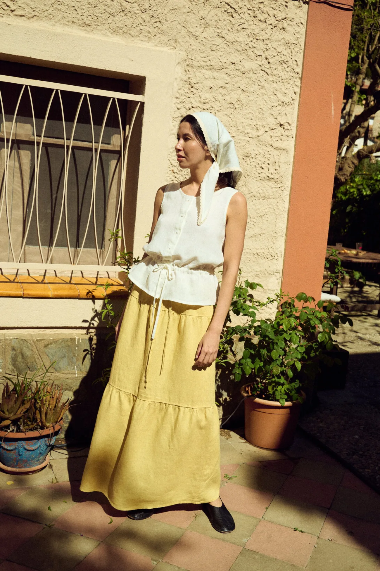 front view of woman wearing tiered butter yellow long linen skirt and white sleeveless linen blouse