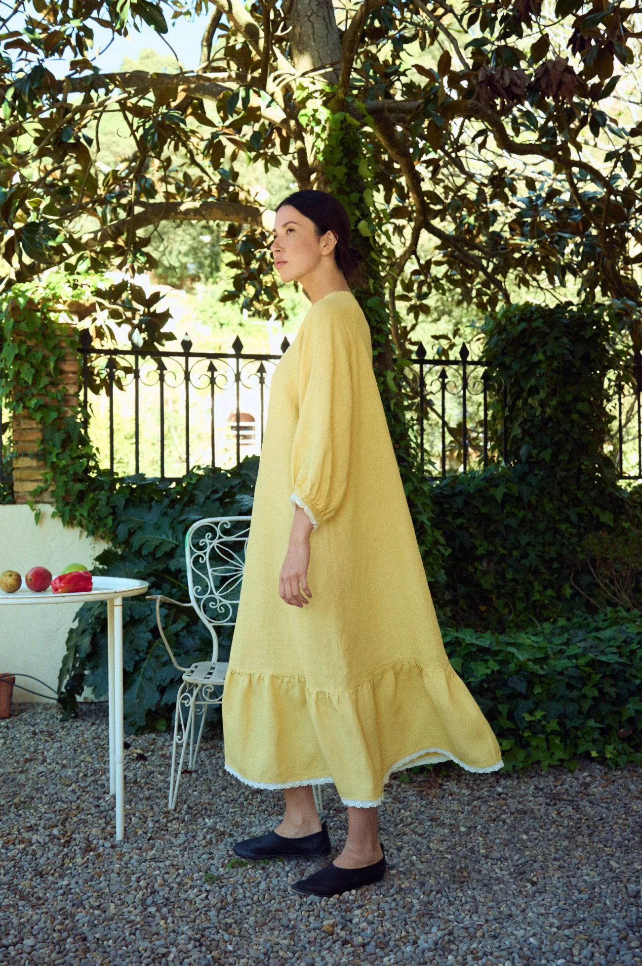 Loose, ankle-length butter yellow linen dress with a relaxed fit, round neckline, soft gathered sleeves, and a tiered hem with subtle lace trim