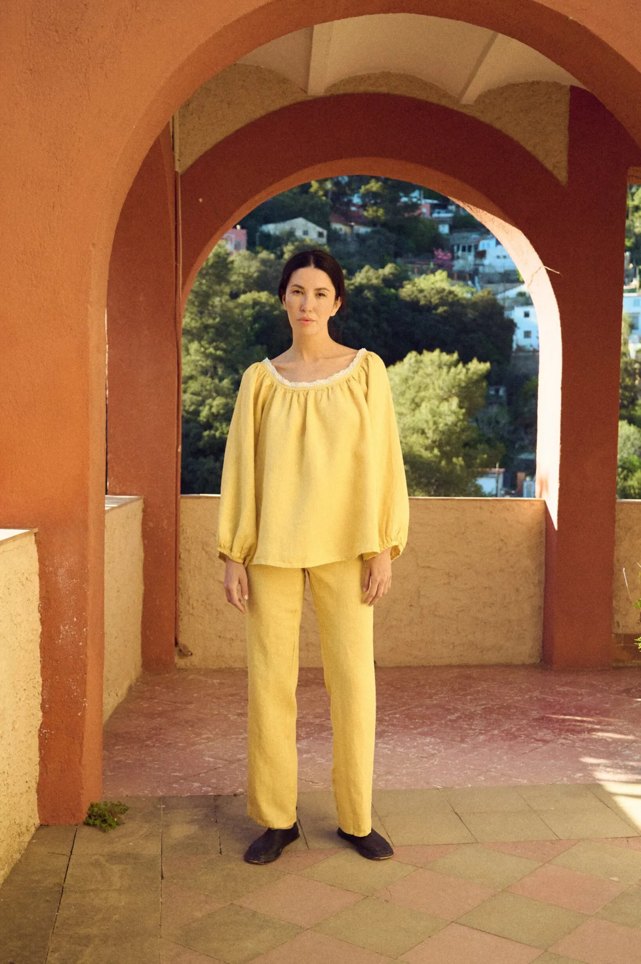 Front view of butter yellow linen blouse with lace-trim scoop neckline and billowy sleeves, paired with matching straight-leg pants