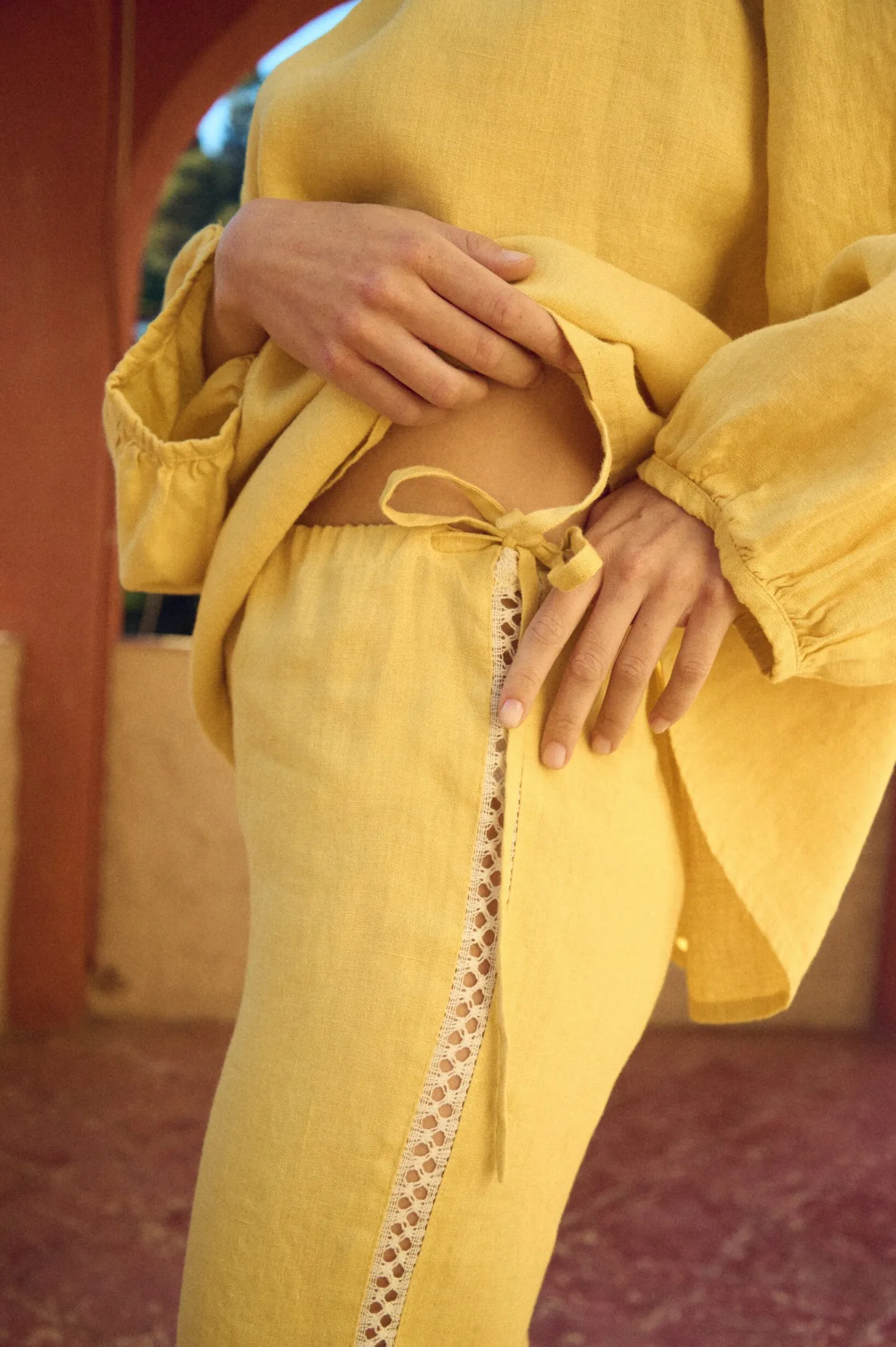 close up of drawstring pants with lace details in butter yellow linen fabric